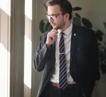 a man in a suit and tie standing in front of a window