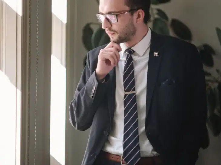 a man in a suit and tie standing in front of a window